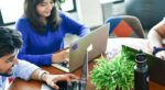 Man and woman working on their laptops at a table